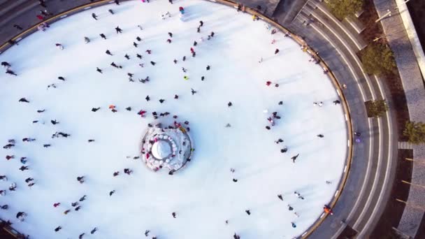Many people are skating on a white outdoor ice rink in the city on winter day. People skating on the surface of a white ice rink. Aerial drone view. Top view. Lifestyle, sport, rest - Séquence, vidéo