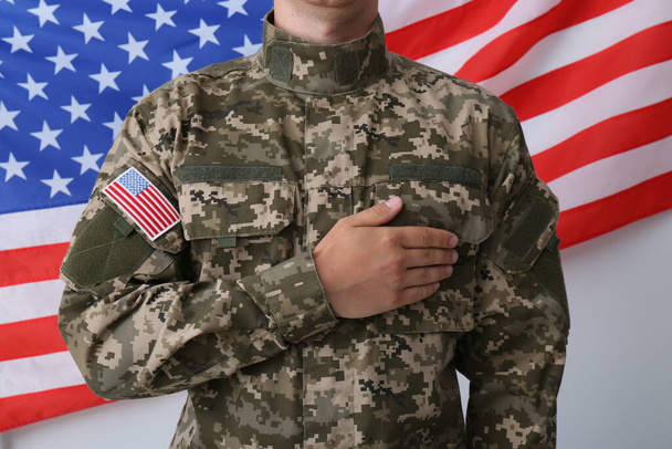 Soldier holding hand on heart near United states of America flag on white background, closeup - Фото, зображення