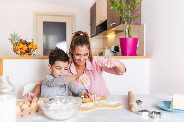 Happy loving family are preparing bakery together. Mother and child son boy are cooking cookies and having fun in the kitchen. Homemade food and little helper. - 写真・画像