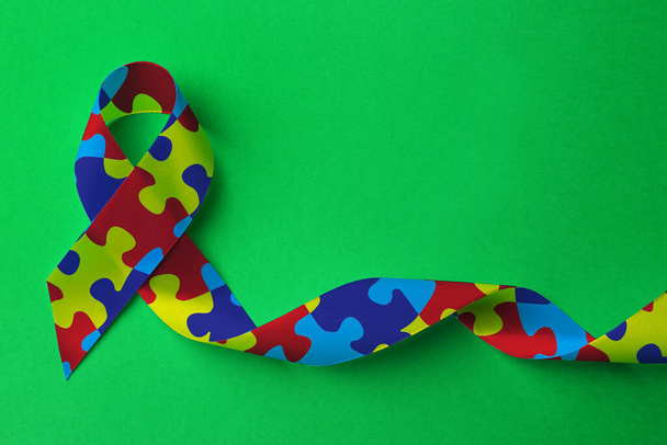 World Autism Awareness Day. Colorful puzzle ribbon on green background, top view - Fotoğraf, Görsel