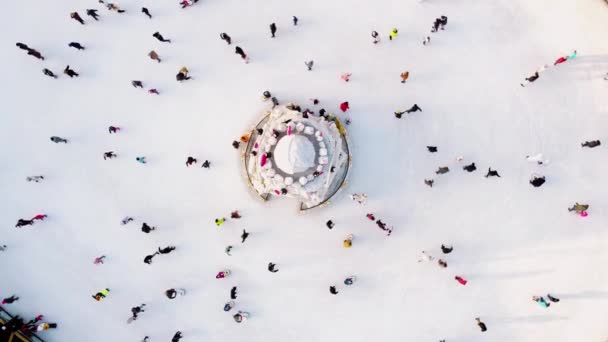 Veel mensen schaatsen op een witte buitenijsbaan in de stad op winterdag. Mensen schaatsen op het oppervlak van een witte ijsbaan. Luchtdrone zicht. Bovenaanzicht. Lifestyle, sport, rust - Video