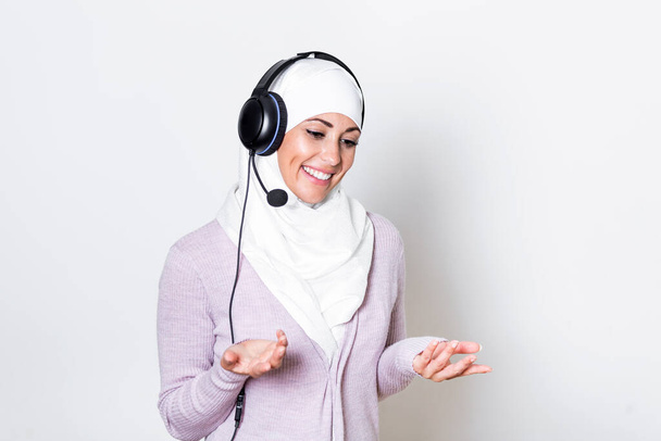 Arab middle eastern businesswoman with headphones customer representative business woman with phone headset helping and supporting online with customer in modern call centre - Photo, image