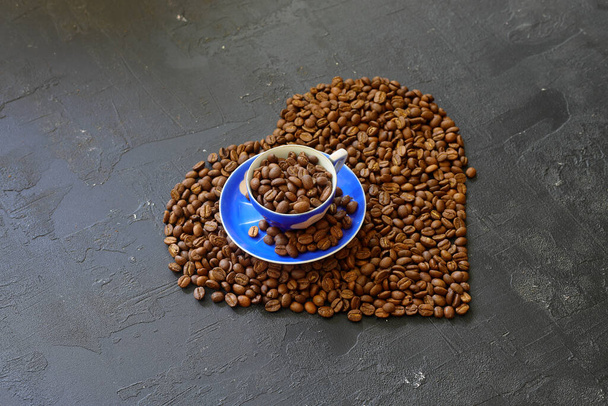 Hartkoffie. Geroosterde koffiebonen in de vorm van een hart op een heldere stenen achtergrond. Concept van koffie liefde, Valentijnsdag, goed humeur, cadeau. - Foto, afbeelding