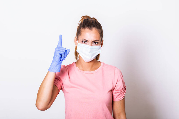 Portrait of young woman wearing face protective mask to prevent Coronavirus and anti-smog. Portrait of young woman wearing face mask showing up with her finger. Covid-19 prevention concept - Φωτογραφία, εικόνα