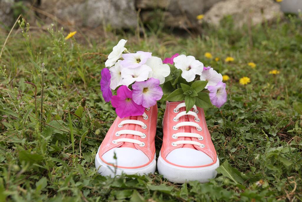 Shoes with beautiful flowers on grass outdoors - Φωτογραφία, εικόνα