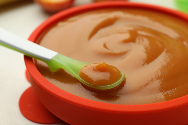 Bowl and spoon with tasty pureed baby food on white table, closeup - Foto, afbeelding