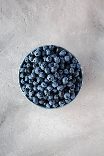 Raw Organic Blueberries in a Bowl on a gray background, top view. Flat lay, overhead, from above.  - Фото, зображення