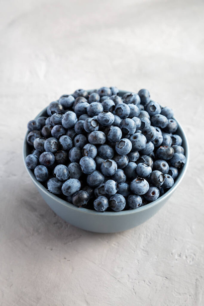 Raw Organic Blueberries in a Bowl on a gray surface, side view.  - Photo, image