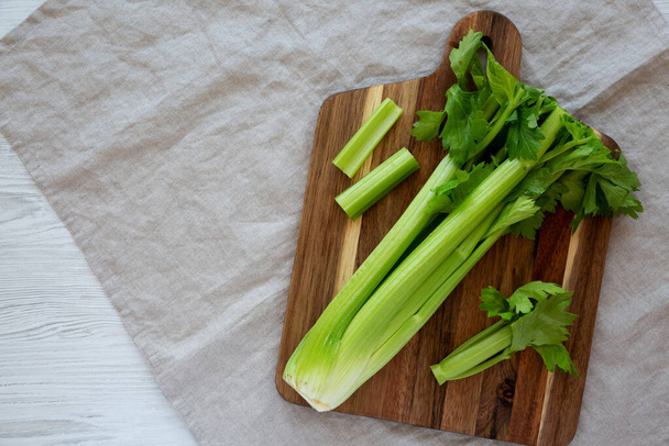 Raw Organic Celery on a wooden board, top view. Flat lay, overhead, from above. Copy space. - 写真・画像