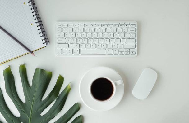 White GWERTY keyboard with a mouse and a cup of coffee on the white table surface. Working place concept. Flat lay of office desk. Copy space for a text. Telework concept - Foto, Bild