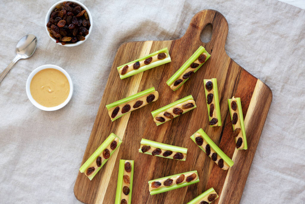 Homemade ants on a log with celery, peanut butter and raisins on a wooden board, top view. - Photo, Image