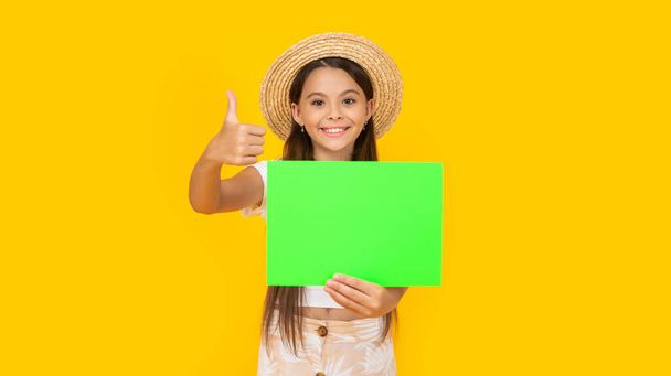 happy teen girl with copy space on green paper on yellow background. thumb up. - Foto, Imagen