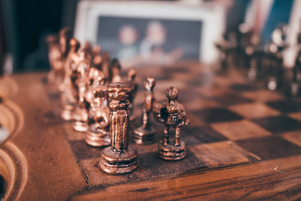 Old vintage wooden chessboard with brass pieces. Selective focus, close up. - Photo, image