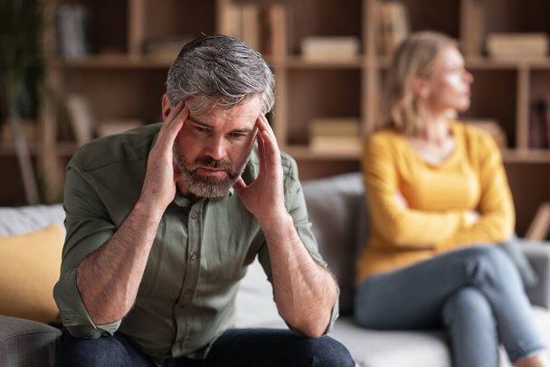 Couple Misunderstanding. Depressed Middle Aged Man Sitting Upset After Argue With Wife, Pensive Male Touching Temples, Tired Of Domestic Conflicts With Spouse, Suffering Mid-Life Crisis - Photo, image