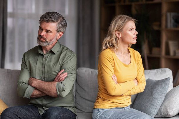 Crisis In Relations. Middle Aged Husband And Wife Offending To Each Other After Argue, Grumpy Spouses Sitting On Couch With Folded Arms, Married Couple Angry After Domestic Quarrel, Free Space - Valokuva, kuva