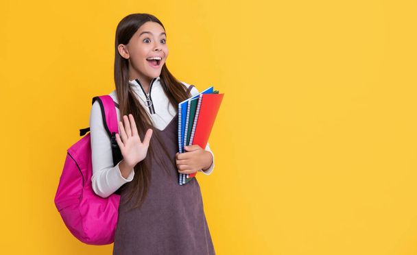 amazed child with school backpack and workbook on yellow background. - Φωτογραφία, εικόνα
