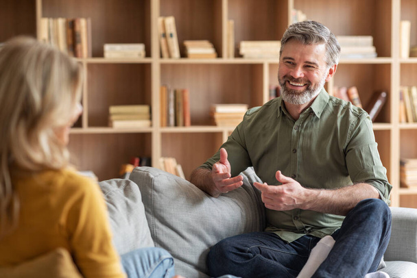 Communication In Marriage. Happy Middle Aged Couple Chatting At Home, Smiling Spouses Talking While Relaxing On Couch In Living Room, Husband And Wife Enjoying Time Together, Selective Focus On Man - Zdjęcie, obraz