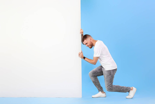 cheerful bearded man pushing board with empty copy space isolated on blue background. mock-up. Advertising. - Фото, изображение