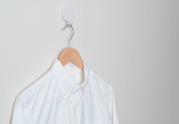 hanging white shirt with wood hanger on wall - Fotoğraf, Görsel