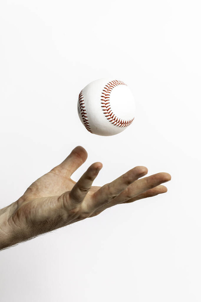 A baseball being tossed from a hand on a white background - Fotó, kép