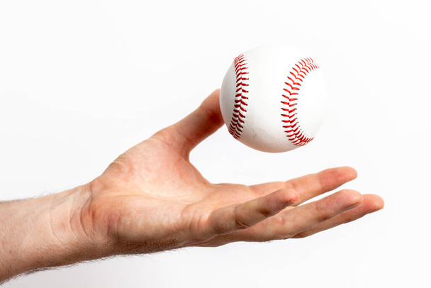 Een honkbal gegooid uit een hand op een witte achtergrond - Foto, afbeelding