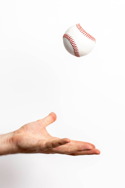 Egy baseball labdát dobnak ki egy kézből, fehér alapon. - Fotó, kép