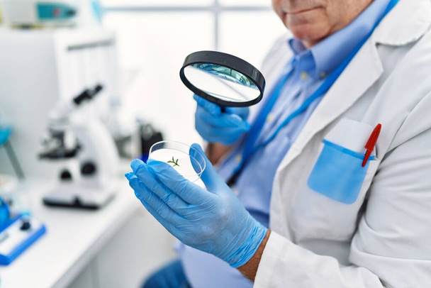 Homme aux cheveux gris d'âge moyen portant un uniforme de scientifique utilisant la loupe au laboratoire - Photo, image
