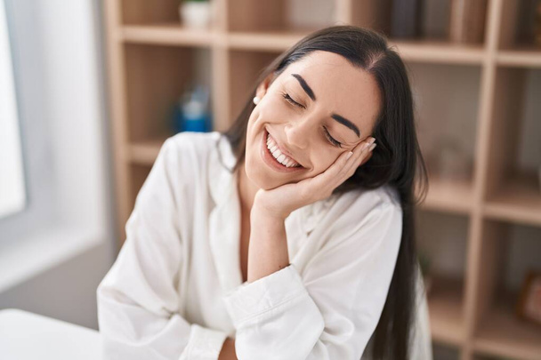 Young hispanic woman smiling confident sitting on table at home - Foto, Imagem