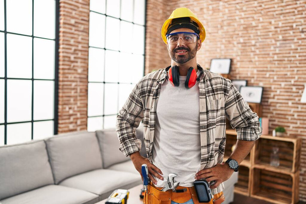 Young hispanic man worker smiling confident standing at home - 写真・画像