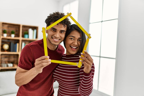 Giovane coppia latina sorridente felice tenuta casa progetto a casa. - Foto, immagini