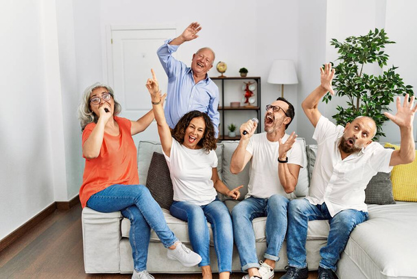 Група друзів середнього віку, які співають вечірку, використовуючи мікрофон вдома
. - Фото, зображення