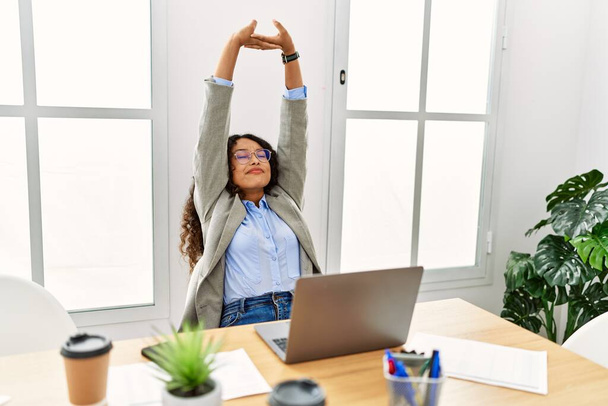 Young latin woman smiling confident stretching arms at office - Photo, Image
