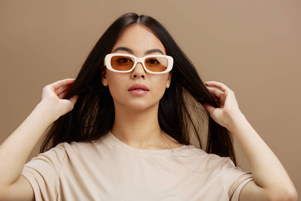 junge Frau in einem beigen T-Shirt mit Brille posiert Mode-Studio-Modell. Hochwertiges Foto - Foto, Bild