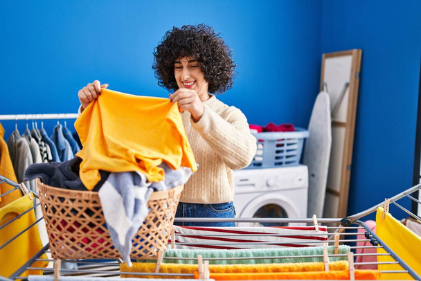 Young middle east woman smiling confident hanging clothes on clothesline at laundry - Foto, Bild