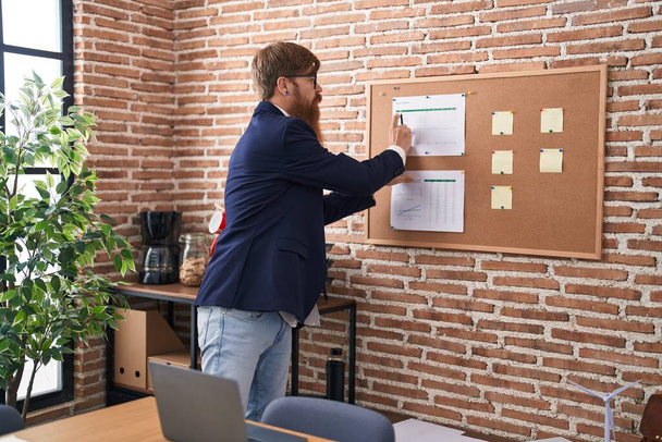 Young redhead man business worker writing on cork board at office - Fotoğraf, Görsel