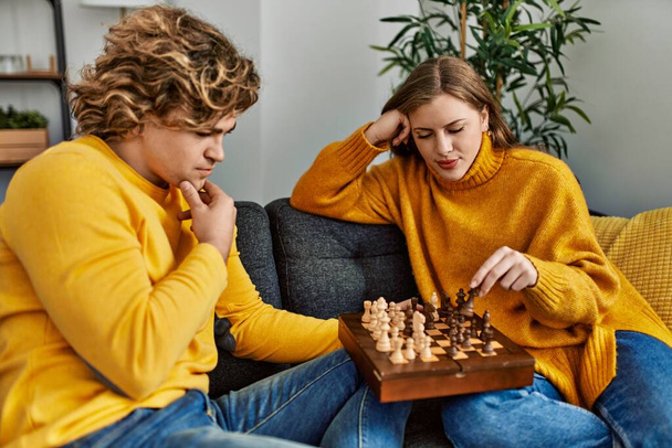Νεαρό καυκάσιο ζευγάρι συγκεντρώνεται παίζοντας σκάκι στο σπίτι - Φωτογραφία, εικόνα