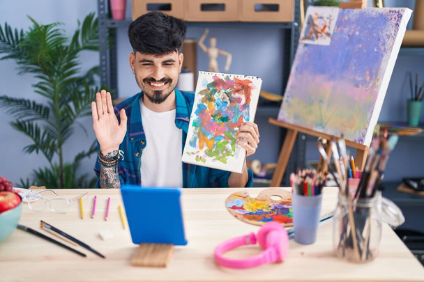 Νεαρός Ισπανός καλλιτέχνης με βιντεοκλήση που δείχνει κλήρωση στο στούντιο τέχνης - Φωτογραφία, εικόνα