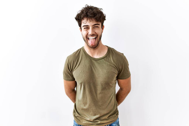 Hispanic man standing over isolated white background sticking tongue out happy with funny expression. emotion concept.  - Fotoğraf, Görsel