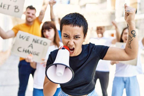 Groep jonge activisten protesteert met spandoek en megafoon in de stad. - Foto, afbeelding