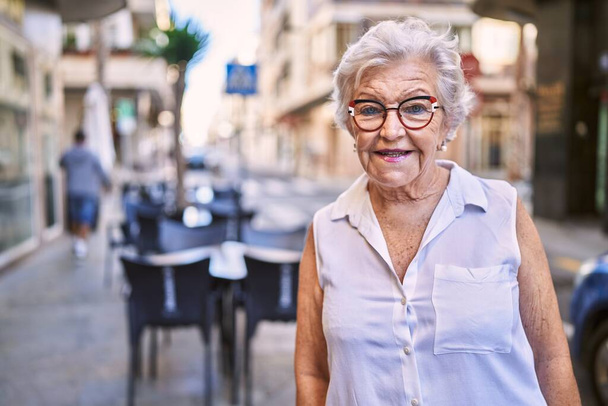 Ältere grauhaarige Frau lächelt zuversichtlich, wenn sie auf der Straße steht - Foto, Bild