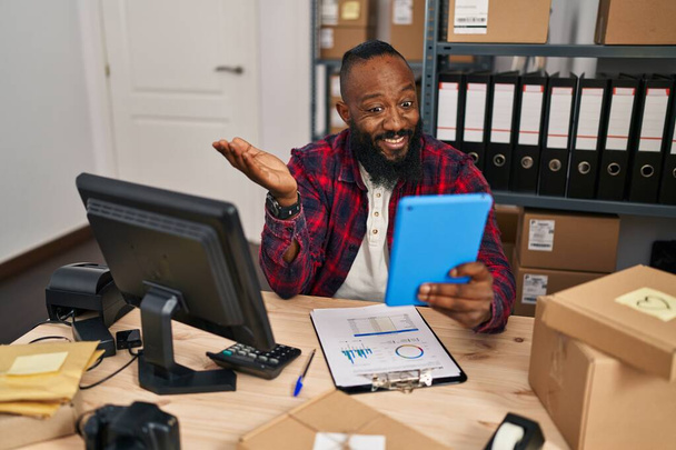 Afro-Amerikaanse man werkt bij kleine bedrijven e-commerce doen video call vieren prestatie met vrolijke glimlach en winnaar uitdrukking met opgeheven hand  - Foto, afbeelding