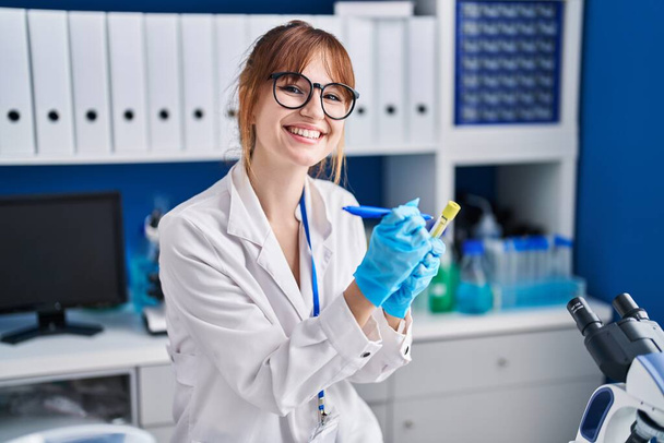 Genç kadın bilim adamı laboratuarda test tüpünde yazıyor. - Fotoğraf, Görsel
