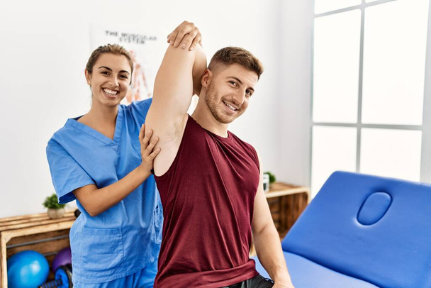 Nuori latino fysioterapisti nainen tehdä käsivarren kuntoutus hoito miehelle klinikalla. - Valokuva, kuva