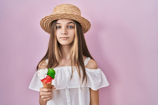 Teenager girl holding ice cream relaxed with serious expression on face. simple and natural looking at the camera.  - Foto, Imagen