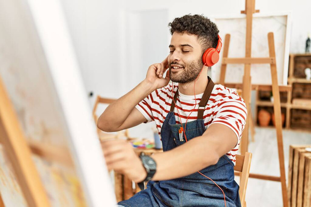 Joven artista árabe escuchando música dibujando en un estudio de arte. - Foto, imagen
