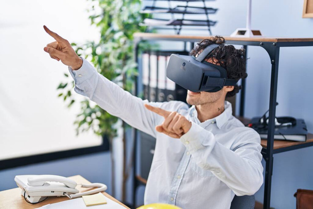 Young hispanic man architect smiling confident using virtual reality glasses at office - Foto, afbeelding