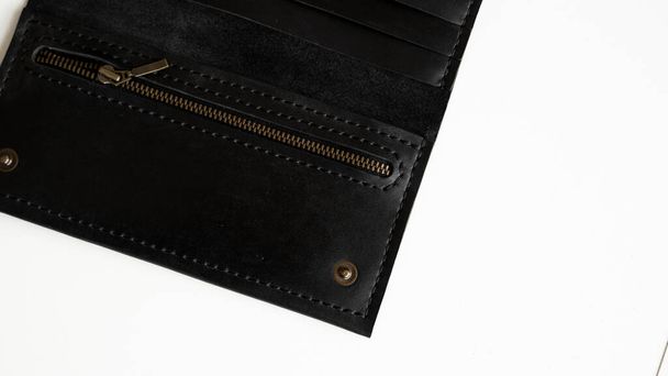 Details of mans handmade wallet on a white surface. Wallet made of genuine black leather with a slots for cards and big zip pocket on a white background. Accessories for men - Фото, зображення