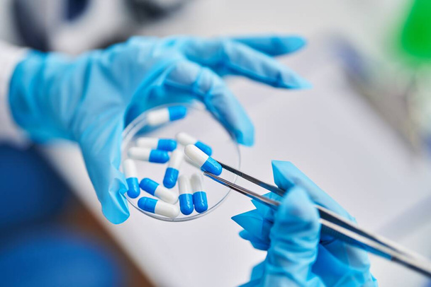 Женщина-ученый средних лет держит таблетки в лаборатории - Фото, изображение