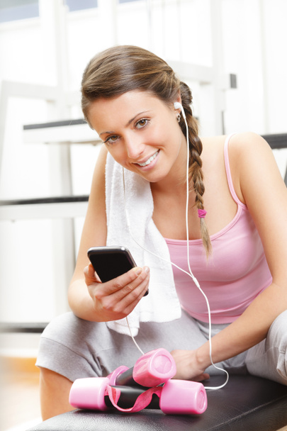Lachende vrouw luisteren naar muziek op de sportschool - Foto, afbeelding
