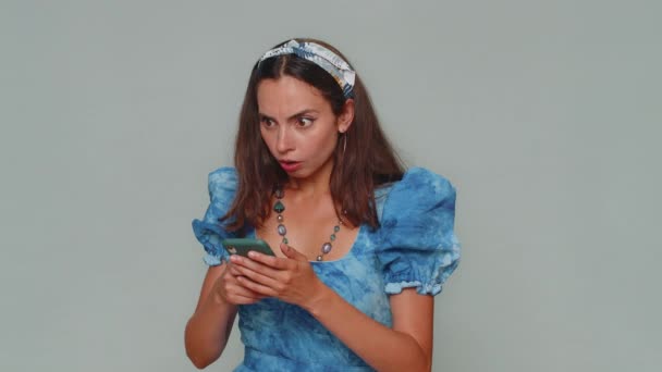 Sad young woman in blue princess dress use smartphone typing browsing, loses becoming surprised sudden lottery results, bad fortune, loss. Adult stylish girl isolated on gray studio background indoors - Video